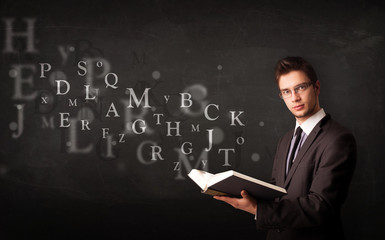 Young man reading a book with alphabet letters