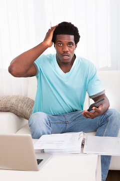 Worried Young Man Holding Calculator
