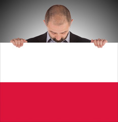 Smiling businessman holding a big card, flag of Poland