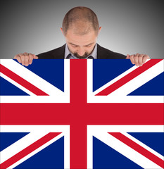 Smiling businessman holding a big card, flag of the United Kingd