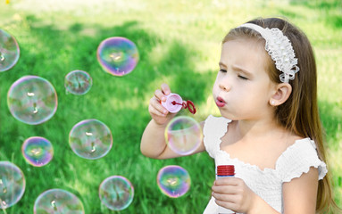 Cute little girl is blowing a soap bubbles