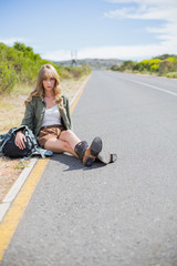 Tired blonde woman sitting on the roadside
