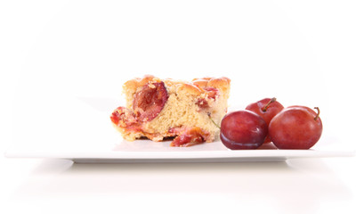 Plum pie decorated with plums on a white plate