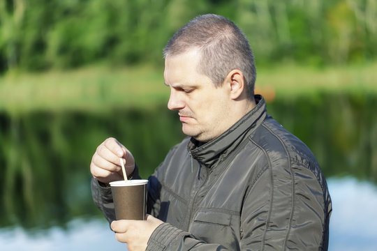 Man with coffee near river