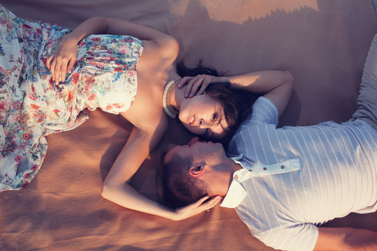 Beautiful couple lying down and kissing on the beach