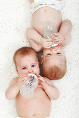 Babies drinking water from feeding bottles