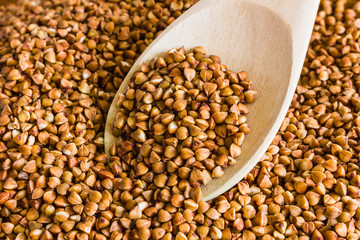 Buckwheat is on the plate with  wooden spoon