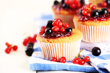 Tasty muffins with berries on white wooden table