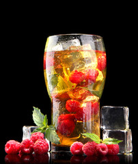 Iced tea with raspberries and mint on black background
