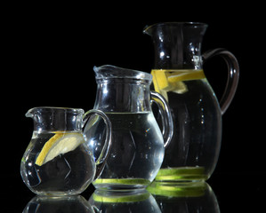 Glass pitchers of water isolated on black