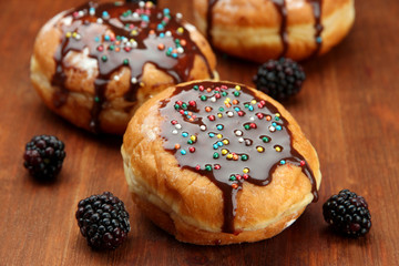 Tasty donuts with chocolate and berries on wooden table