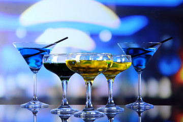Glasses of cocktails on bright background