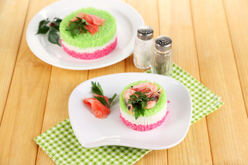 Colored rice on plates on napkin on wooden table