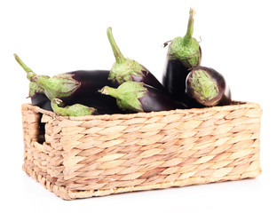 Fresh eggplants in wicker basket isolated on white