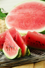 Ripe watermelons on wicker tray  on table on wooden background