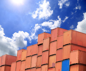 Stacked cargo containers in storage area with blue sky