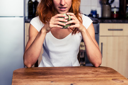 Woman drinking from cup in her kitchen