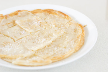 Roti Canai Pour Condensed milk and sprinkle sugar on top,cut int