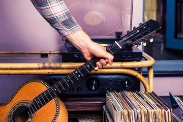 Hand picking up guitar next to box of vinyl