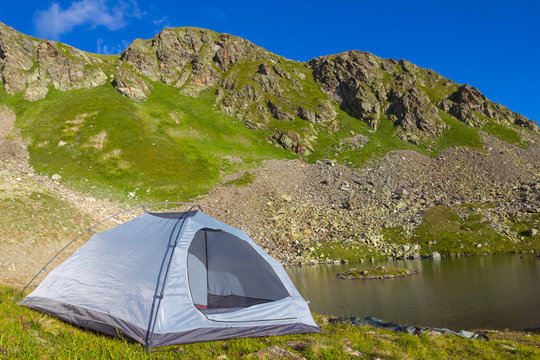 white touristic tent on a mountain lake coast © Yuriy Kulik
