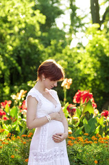 Beautiful pregnant woman in green garden