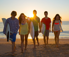 Surfers boys and girls group walking on beach