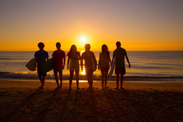 Surfers boys and girls group walking on beach