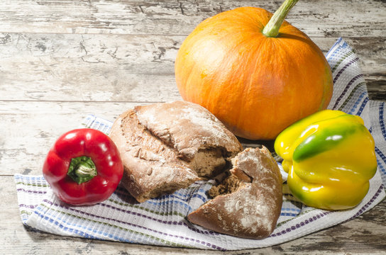Bread, pumpkin and pepper on old wooden table