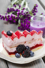 Pink layer cake decorated with fresh fruits on wooden table
