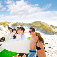 Obraz premium Surfer teen boys and girls group walking on beach