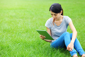 Asian woman using tablet on grassland