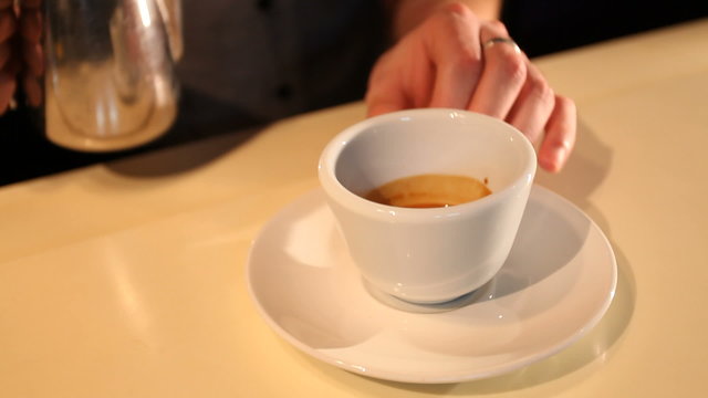 Barman makes picture on coffee with milk