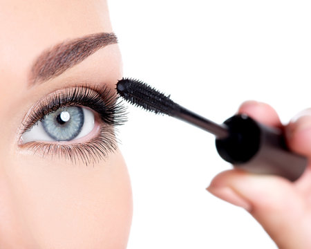 woman applying mascara on eyelashes