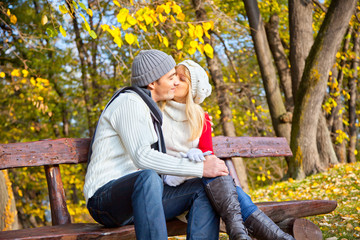Fototapeta premium Young romantic couple on a bench in park.