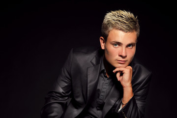 Elegant young handsome man over dark. Studio fashion portrait.