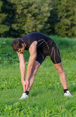 Young sportsman stretching before workout in park