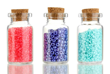 Little bottles full with colorful beads isolated on white