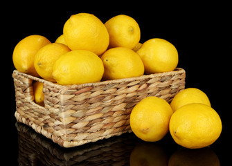 Ripe lemons in wicker basket isolated on black