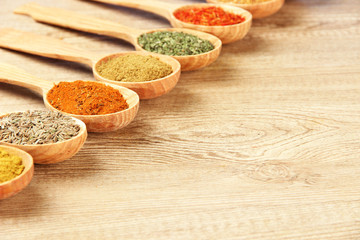 Assortment of spices in wooden spoons on wooden background