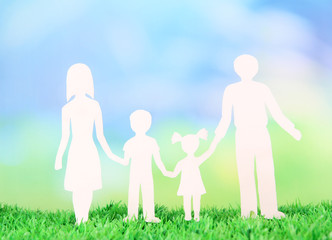 Family from paper on grass on bright background