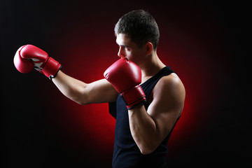 Fototapeta na wymiar Handsome young muscular boxer on dark background
