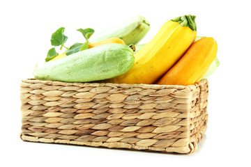 Raw yellow and green zucchini in wicker crate, isolated on