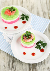 Colored rice on plates on napkin on wooden table