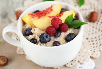 Oatmeal in cup with berries on napkins on wooden table