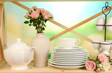 Lots beautiful dishes on wooden shelf on natural background