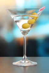 Martini with green olives on table in bar