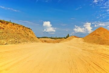 sandy road between hills in sunny summer day