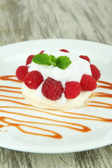 Tasty meringue cake with berries on wooden table