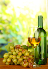Fototapeta na wymiar Ripe grapes, bottle and glass of wine, on bright background
