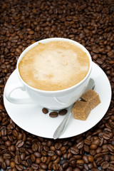 cup of cappuccino with brown sugar on coffee beans